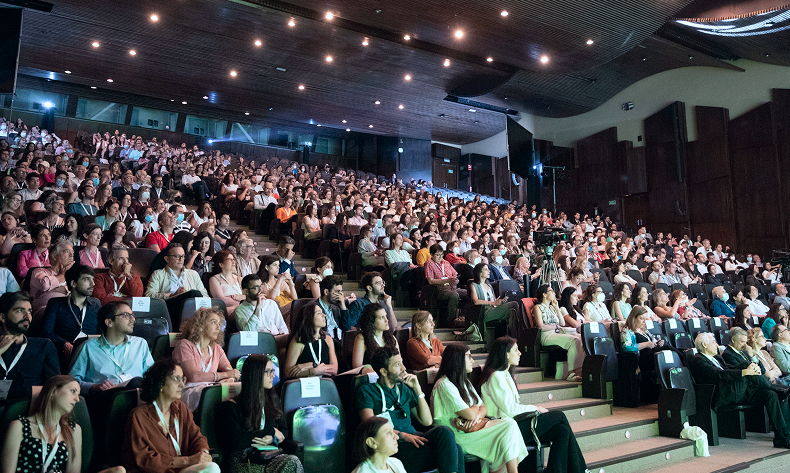 Gran auditorio lleno de asistentes atendiendo a una conferencia profesional en un congreso